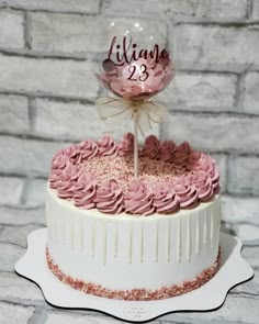 a white cake with pink frosting and a large balloon on top that says lilie 23