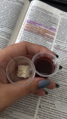 a person is holding two small plastic containers with food in them on top of an open bible