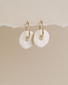 two white earrings hanging from a hook on a wall