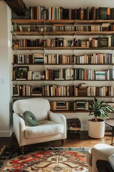 a white chair sitting in front of a book shelf filled with books on top of it