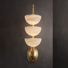 The Triple Alabaster Wall Sconce exudes elegance with its blend of snowflake stone and metal. Featuring three beautifully crafted alabaster shades, this sconce emits a soft, diffused light that creates a serene ambiance. The brass metal frame complements the natural patterns of the alabaster, making it a stylish and sophisticated addition to any room. Inspired by the timeless beauty of alabaster and the warmth of brass, this sconce is perfect for enhancing hallways, living rooms, or bedrooms ... Crystal Chandelier Kitchen, Hallway Wall Lights, Room Inspired, Tiffany Style Table Lamps, Chandelier Art, Wall Lights Living Room, Kitchen Island Chandelier, Flushmount Ceiling Lights