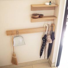 two wooden shelves with umbrellas and hats hanging on them, in front of a window