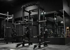 an empty gym with squat racks and weight machines in the background, at night time