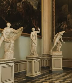 marble statues in a room with paintings on the wall