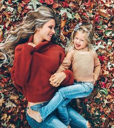 mother and daughter laying on the ground in autumn leaves