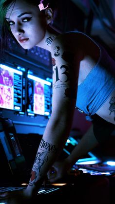 a woman with tattoos on her arm is playing dj's in front of monitors