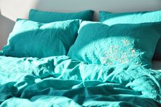 an unmade bed with green sheets and pillows