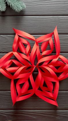 an origami snowflake made out of red paper sitting on top of a wooden table