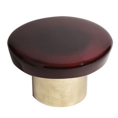 a close up of a knob on a white surface with a red top and gold base