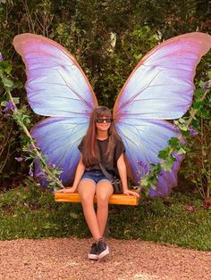 a woman sitting on a swing with a butterfly wings