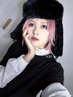 a woman with pink hair wearing a black hat