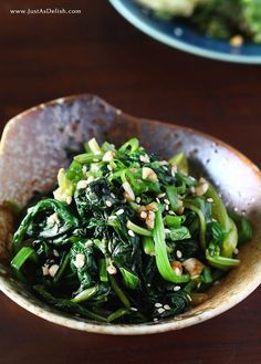 a bowl filled with green vegetables on top of a wooden table