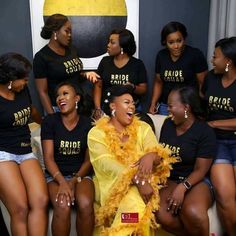 a group of women sitting next to each other wearing black shirts and yellow feathers on their heads