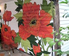 an orange flower painted on the side of a white wall next to a glass table