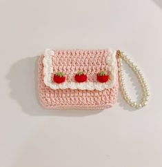 a pink crocheted purse with two strawberries on the front and white trim