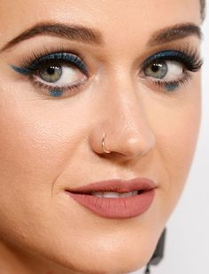 a close up of a woman with blue eyeliners on her face and nose