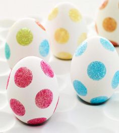 four decorated eggs sitting on top of a white plate with polka dots painted on them