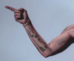 a man with tattoos on his arm pointing at something