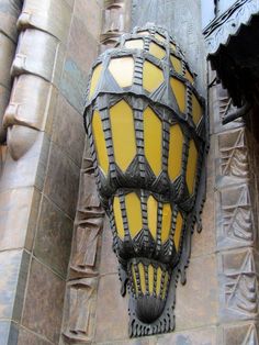 a yellow and black street light on the side of a building with intricate carvings around it