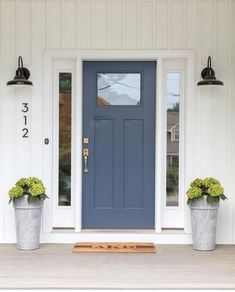 a blue front door with two planters on the side and numbers painted on it