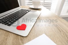 an open laptop computer sitting on top of a wooden desk next to a cup of coffee