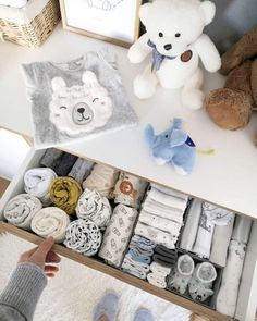 two teddy bears are sitting on the shelf next to some baby clothes and other items