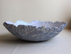 a gray bowl sitting on top of a table next to a white wall and floor