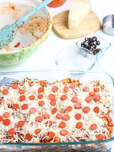 a casserole dish with pepperoni and cheese on top, next to other ingredients