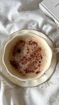 a cup of hot chocolate sitting on top of a white saucer next to a book