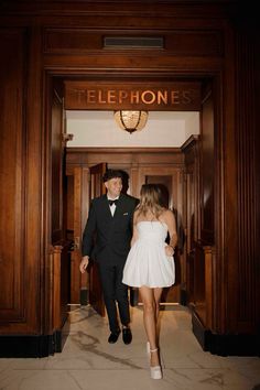 a man in a tuxedo and a woman in a white dress are walking into an elevator