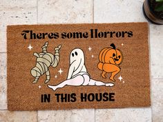 a door mat that says, there's some horrors in this house with two ghost