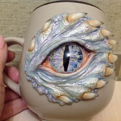 a hand holding a coffee mug with an eye on it