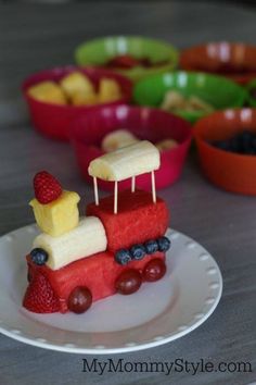 a plate that has fruit on it and some food in the shape of a train