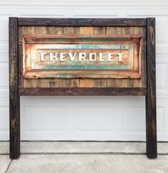 an old sign that is sitting on the side of a garage door in front of a building