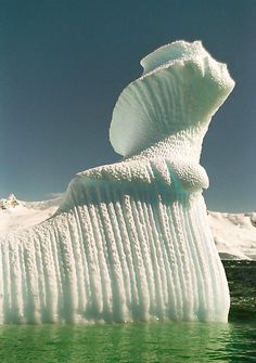 an iceberg is floating in the water with snow on it's sides and bubbles coming out of its back