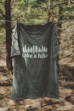 Take A Hike graphic t-shirt. Each t-shirt is pressed house on a comfort colors unisex shirt. T-shirts are made of a soft cotton blend and features a vibrant direct to fabric transfer design that won't fade or crack.  COLOR PICTURED: HEMP Shop our wanderlust inspired t-shirt collection. Perfect for those who enjoy hikin Take A Hike Shirt, Cotton Crew Neck T-shirt For Outdoor Activities, Custom Print Short Sleeve T-shirt For Outdoor, Cotton T-shirt With Letter Print For Camping, Green Graphic Print T-shirt For Camping, Green Graphic Tee For Outdoor, Graphic Tee With Text Print For Camping, Pre-shrunk Green T-shirt For Camping, Green Graphic Tee For Outdoor Activities