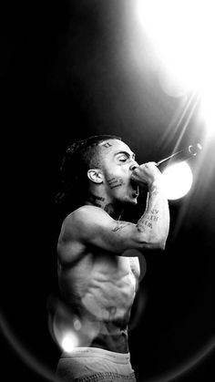 a shirtless man holding a microphone in his right hand