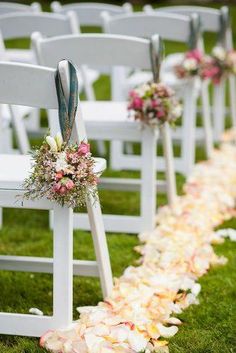 the aisle is lined with white chairs and decorated with pink, peach and green flowers