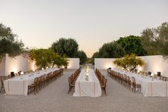 an outdoor dining area with long tables and chairs set up for dinner in the evening