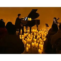 people are sitting in front of candles and a piano