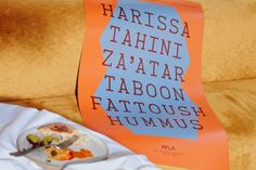 a plate of food sitting on top of a white cloth next to an orange book