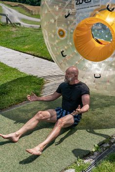 a man sitting on the ground next to an inflatable object with his legs spread out