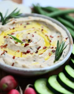 a bowl filled with dip surrounded by sliced cucumbers