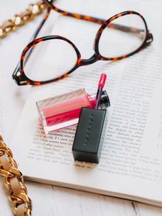 an open book with glasses and lipstick on it