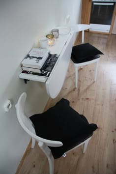 a white table with two chairs and a book on top of it next to a wall