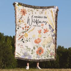 a woman standing in front of a banner with flowers on it that says, consider the wildflowers