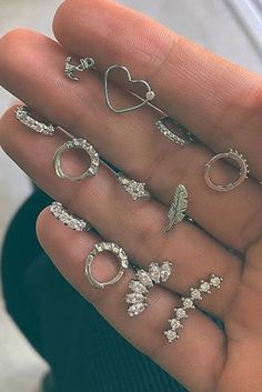 someone is holding their hand full of different rings and earring sets, all in the shape of hearts