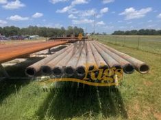 large pipe laying on the ground in front of an open field with other pipes behind it