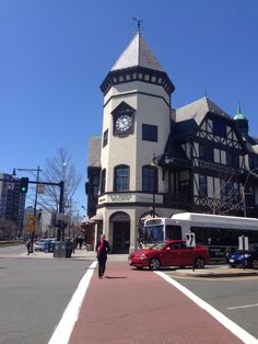 a white bus parked in front of a tall building with a clock on it's face