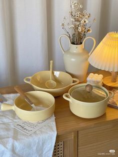 a table topped with bowls and dishes next to a lamp